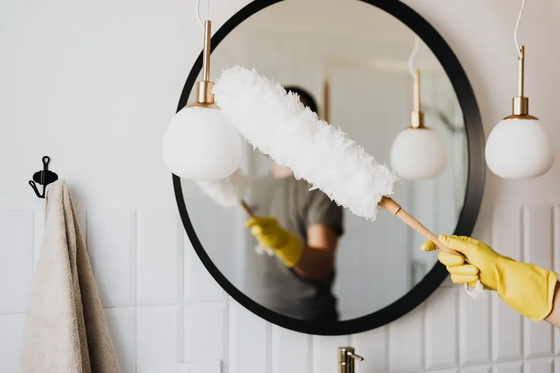Feather duster passing across a round mirror in a styled hallway