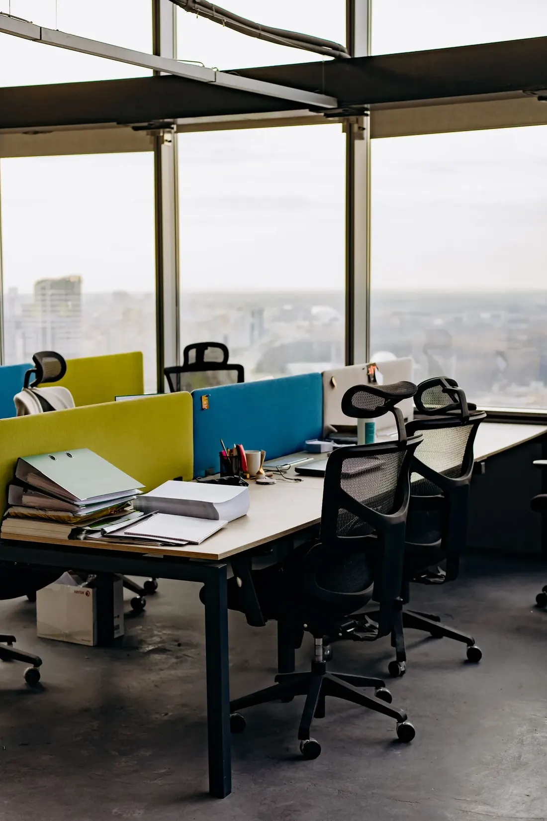 Office desks beside tall windows before the working day begins