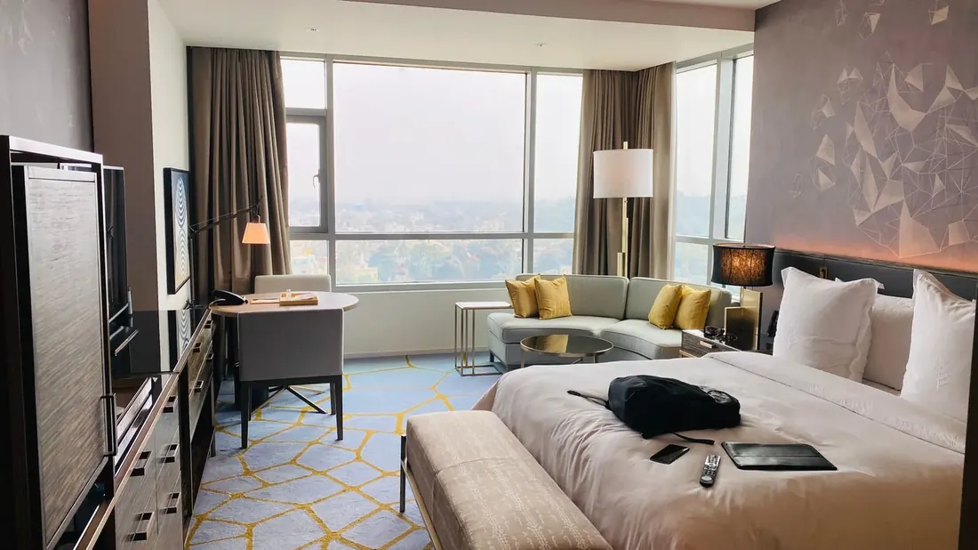 Hotel guest room with the bed made and curtains open