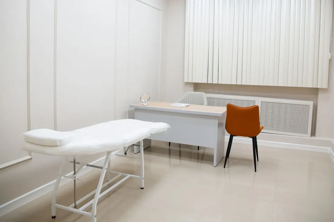 Bright clinical room with an examination table and a single chair